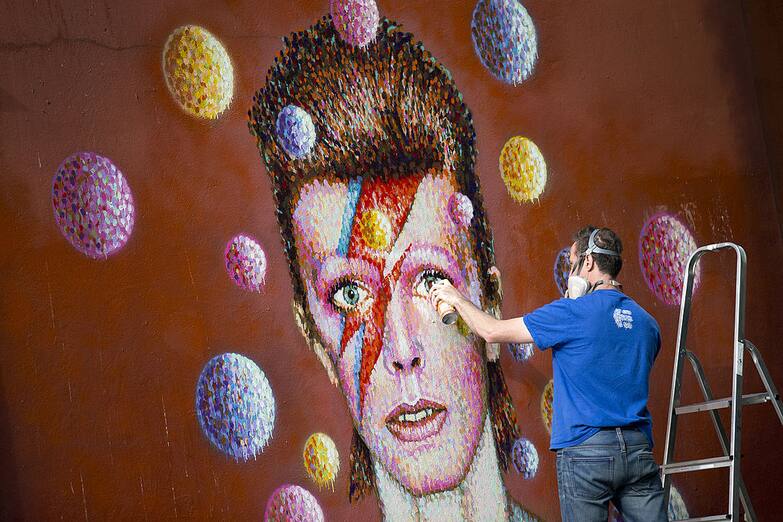 Australian street artist James Cochran, also known as Jimmy C, puts the finishing touches on a large 3D wall portrait of British musician David Bowie in Brixton, South London, on June 19, 2013. The artwork is based on the iconic cover for Bowies 1973 album, Aladdin Sane. AFP PHOTO/JUSTIN TALLIS (Photo credit should read JUSTIN TALLIS/AFP via Getty Images)