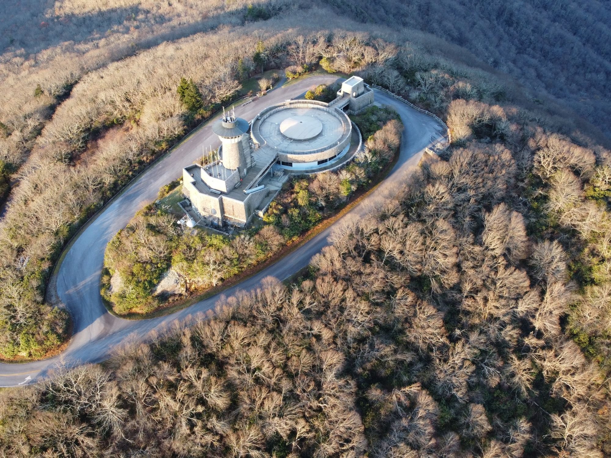 Aerial shot of a building located on a top of the Brasstown bald mountain during the day.