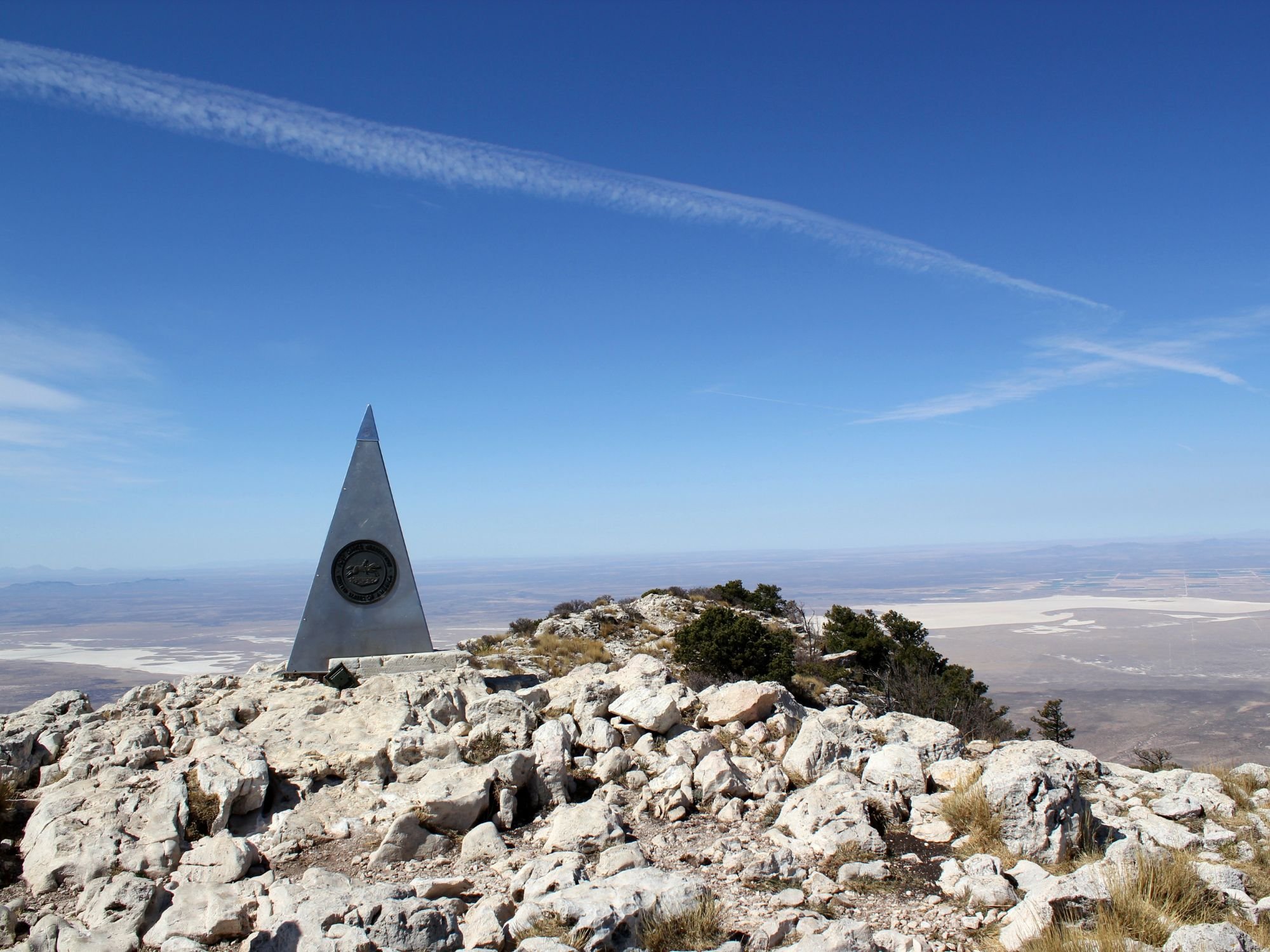 A stainless steel small pyramid on top of a rocky peak.