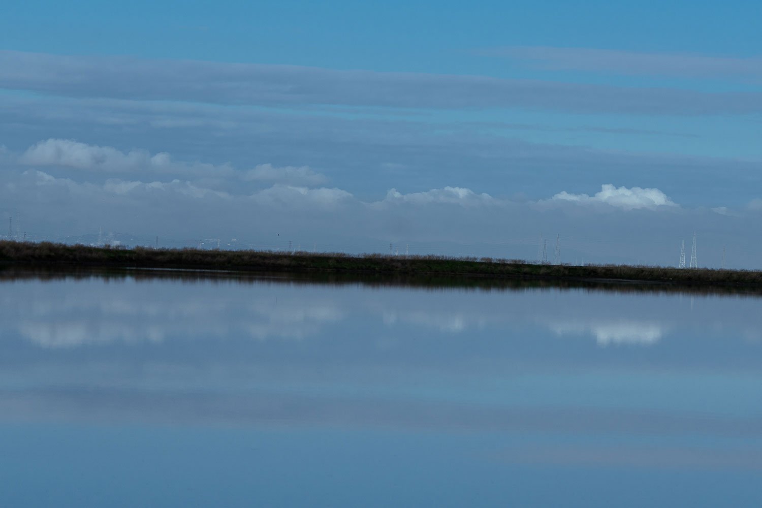 A view across a salt pond with the sky reflected into the pond.