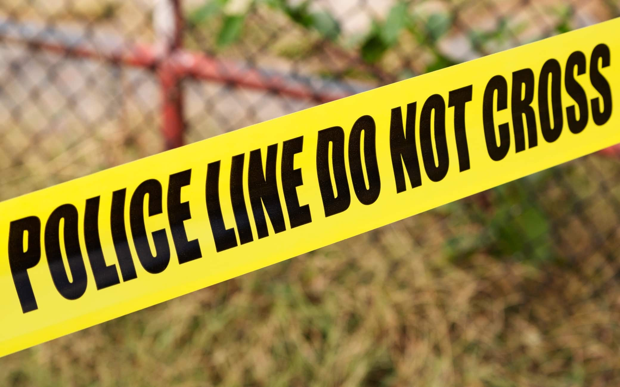 A yellow barricade tape bears the words 'police line do not cross' in Washington DC, USA. The tape marks the periphery of a crime scene.