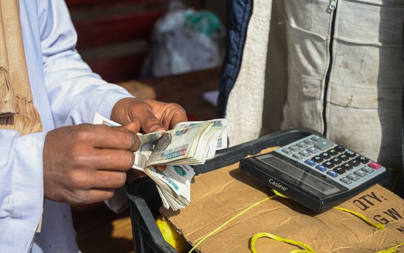 A customer counts out Egyptian pound banknotes to pay a vendor for a purchase at the El Obour wholesale market in Cairo, Egypt, on Tuesday, Jan. 23, 2024. Egypt's credit outlook was cut to negative from stable by Moody's Investors Service while the pound's weakening on the black market accelerated, in a sign of the country's worsening economic plight. Photographer: Islam Safwat/Bloomberg via Getty Images