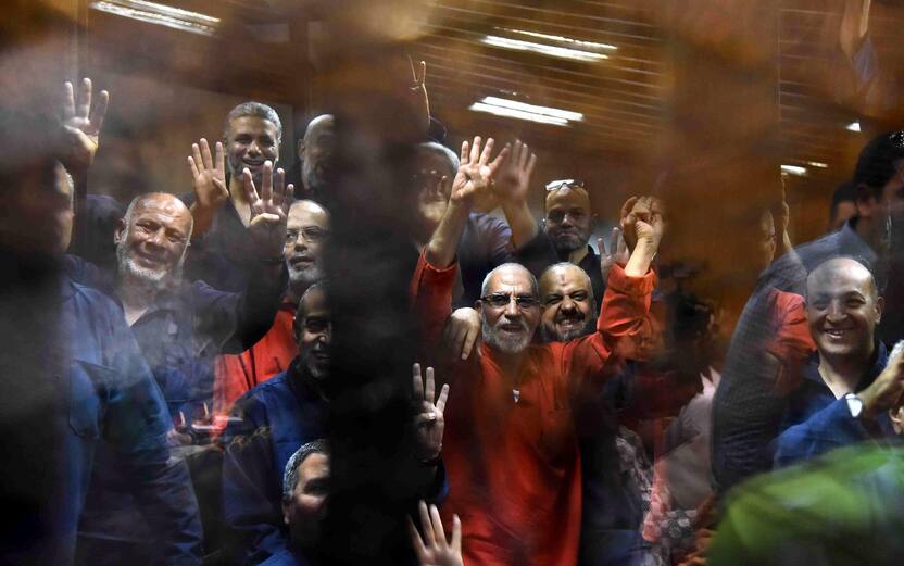 epa04802469 Muslim Brotherhood Supreme Guide Mohammed Badie (C, wearing red) along other Brotherhood members react inside defendants' cage in the courtroom during a trial session, in Cairo, Egypt, 16 June 2015. A Cairo court on 16 June 2015 sentenced former president Mohamed Morsi to death over jailbreaks during Egypt's 2011 uprising. Muslim Brotherhood Supreme Guide Mohammed Badie, former parliament speaker Saad al-Katatni and three other co-defendants also received the death penalty in the case. In a related case, three Muslim Brotherhood leaders were sentenced to hang for conspiring with foreign powers. Morsi and 16 others received life sentences in that case. EPA/ALI MALKI / ALMASRY ALYOUM EGYPT OUT