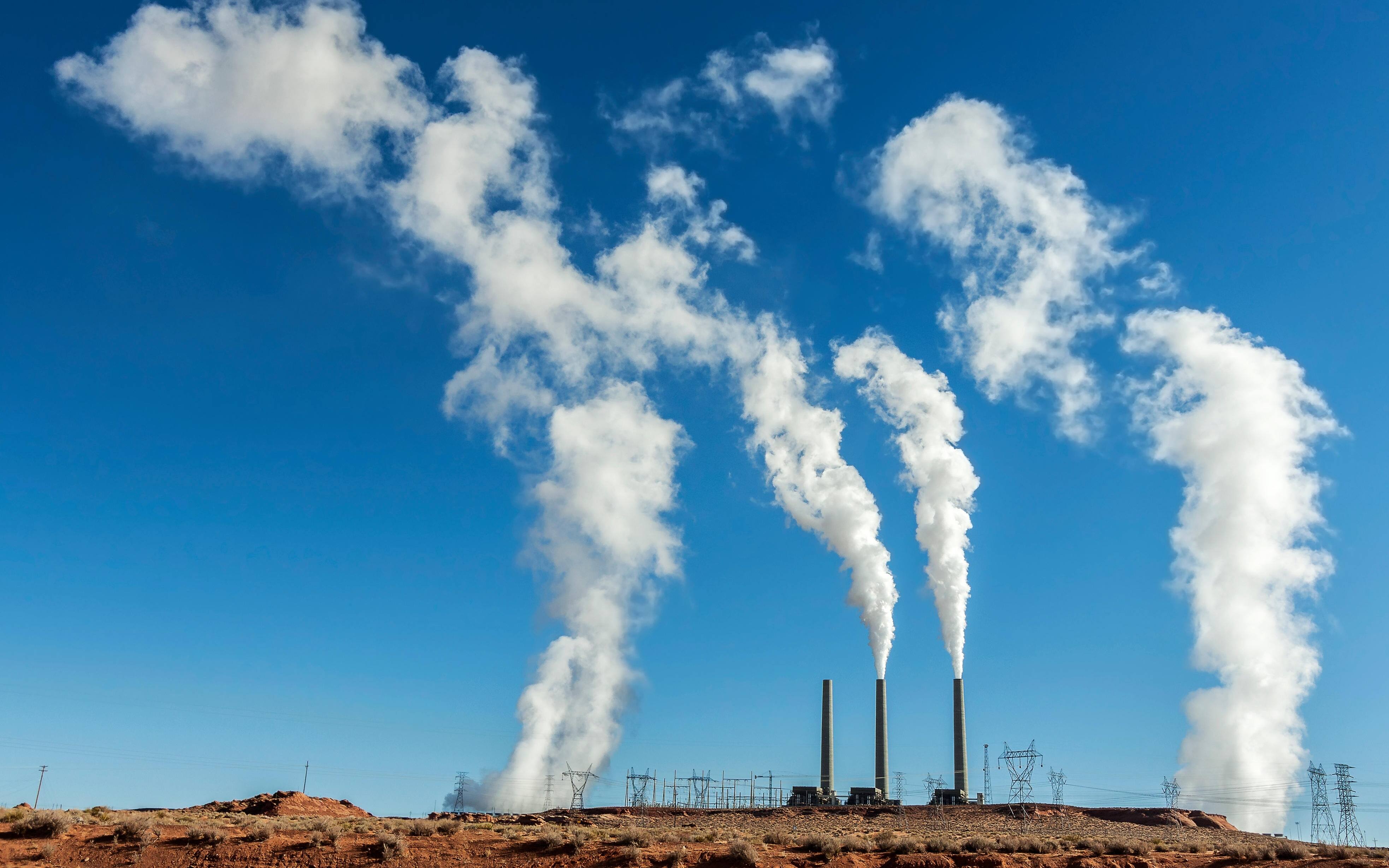 Power industry infrastructure. Chimneys with white smoke on a blue sky, USA.