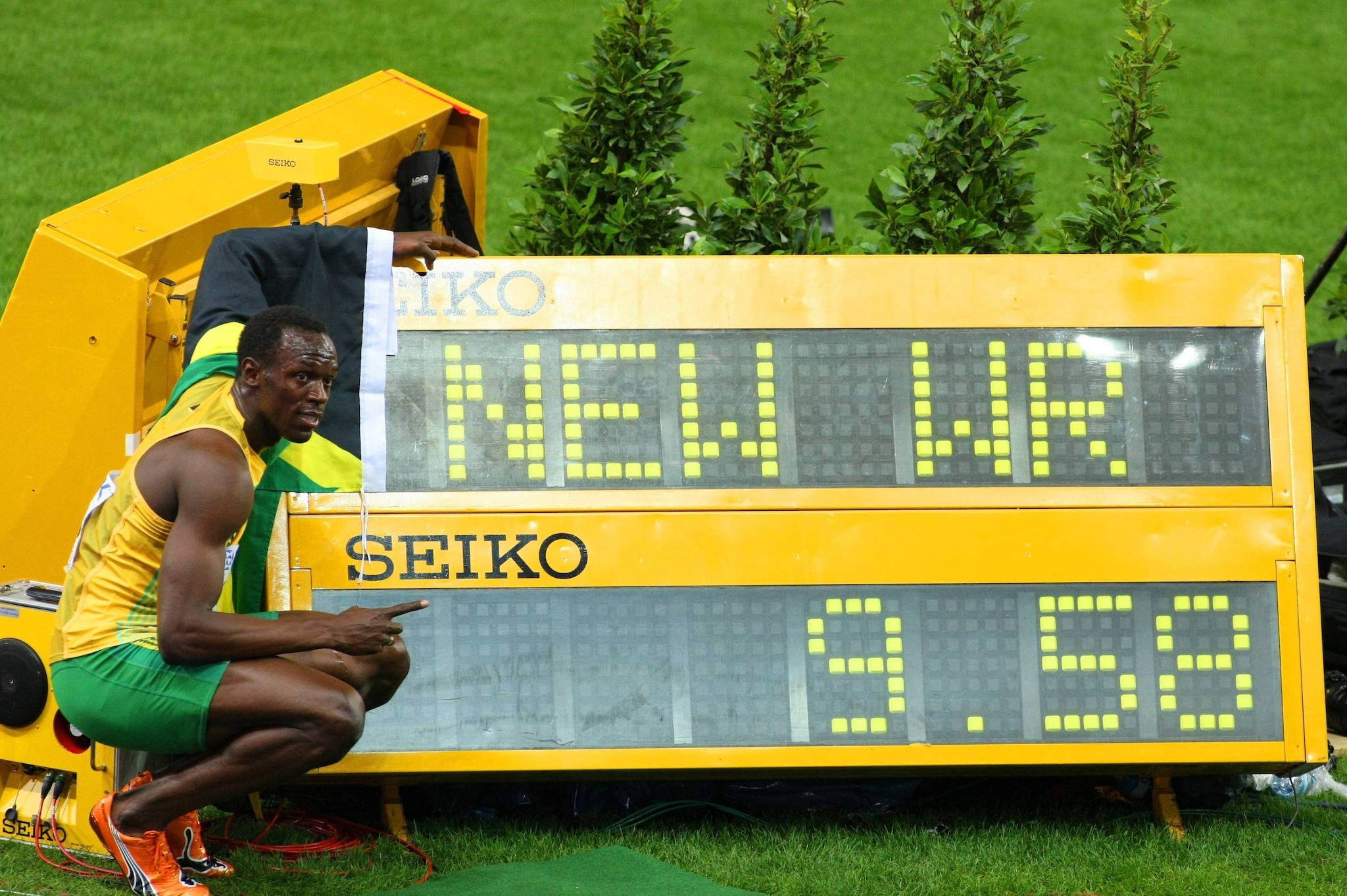 Usain Bolt posa al fianco del tabellone col suo record dei 100 metri a Berlino 2009